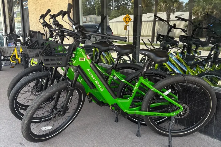 Green electric bikes parked in front of Salty's Bike Rentals shop.