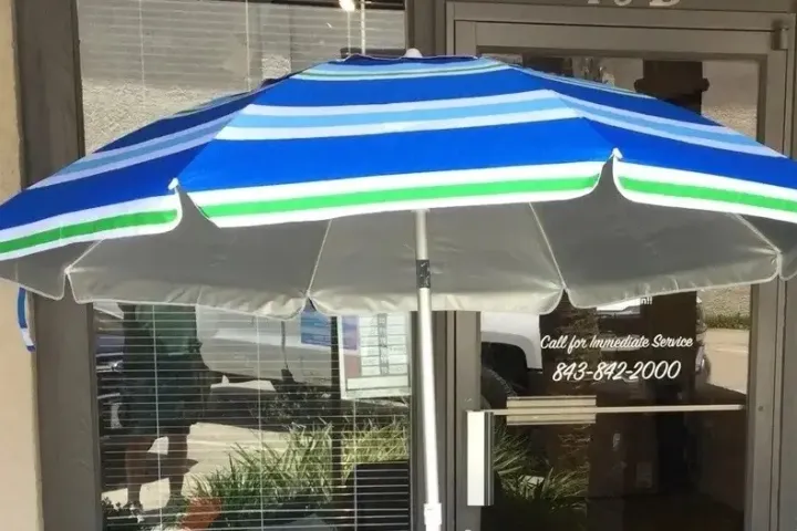 Blue and green striped umbrella outside a glass door with signage.